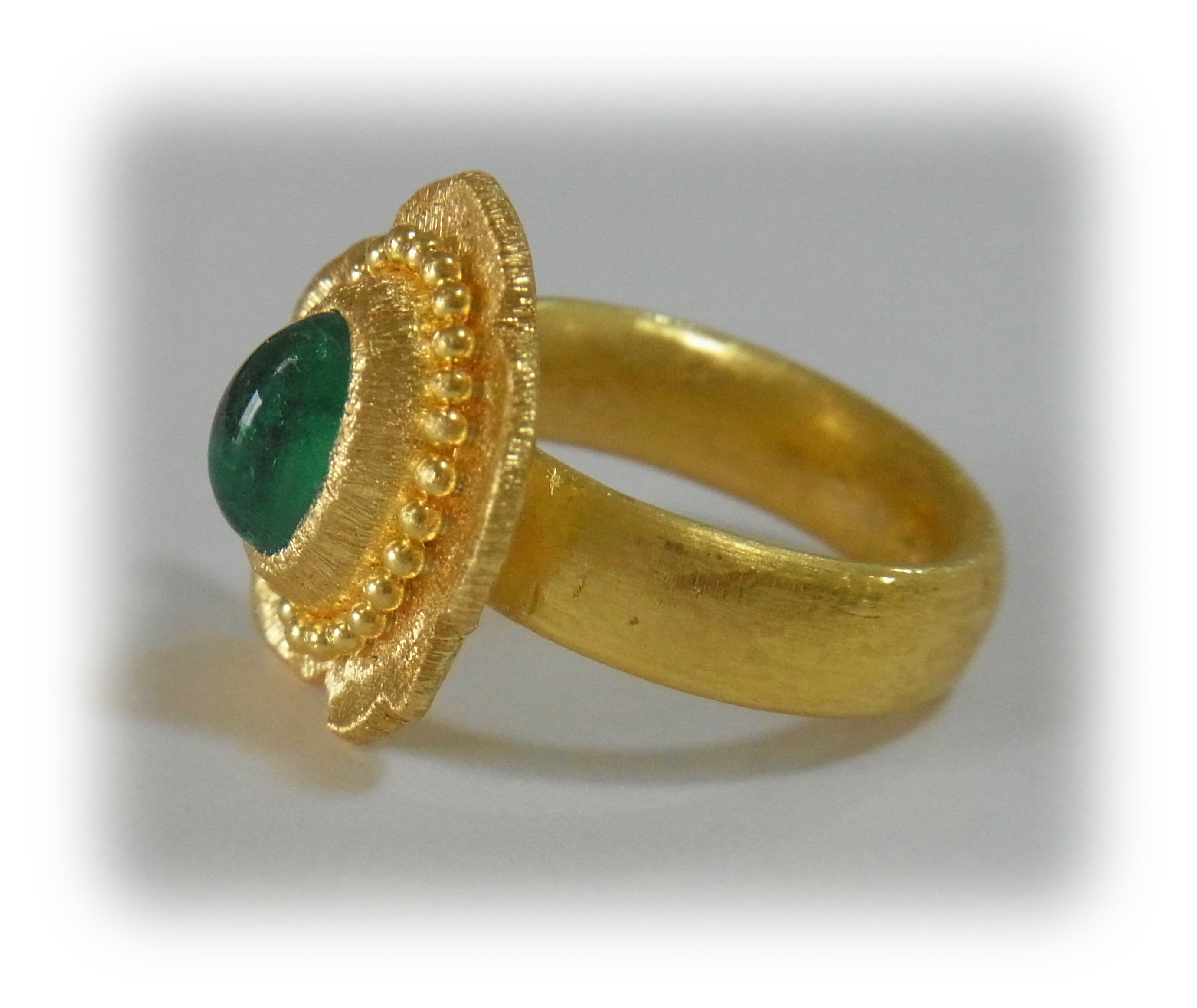 Gold ring with a cabochon-cut emerald; granulation decoration on the bezel rim (side view)